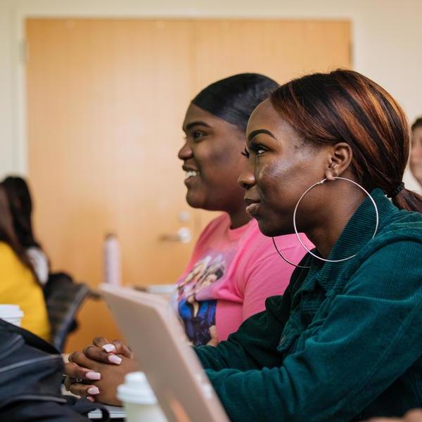 Two Agnes Scott neuroscience major students taking notes in the class on their laptops.